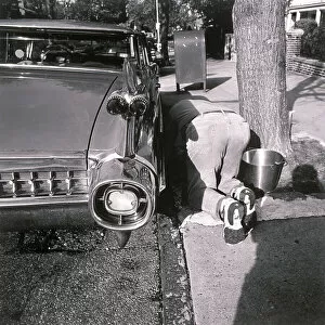 Henri Silberman Collection Gallery: Man kneeling on ground and washing car