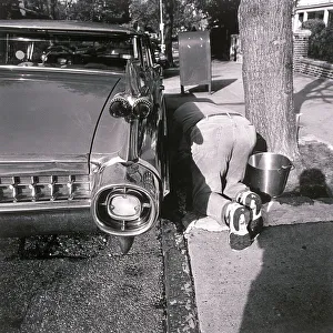 Henri Silberman Collection Gallery: Man kneeling on ground and washing car