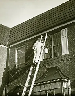 Unknown Age Prints: Man on ladder painting shutter (Rear view), (B&W), low angle view