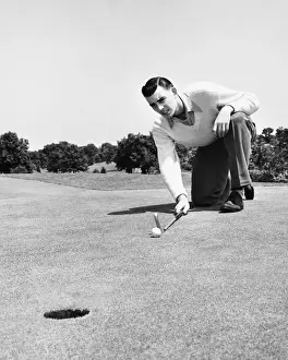Crouching Prints: Man lining up golf shot on putting green