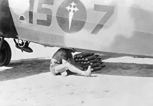 Burgos Prints: Man Loading Bombs into Base of Airplane