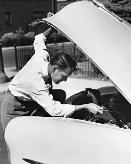 Examining Prints: Man looking under hood of car