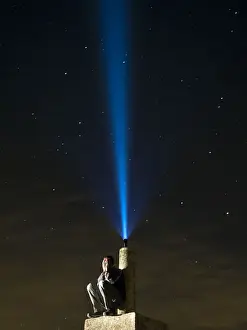 Worried Prints: Man on top of a mountain, desperate hands on the lost face at night with a flashlight signal