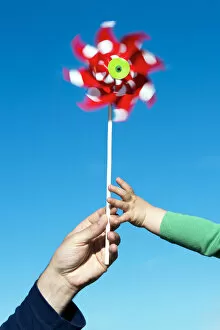 Man passing a wind wheel to a child, symbolic image for environmental education, alternative energy and sustainability