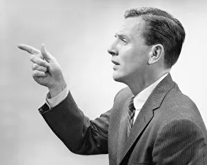 Man pointing with index finger, posing in studio, (B&W), close-up