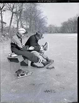 Ice Rink Prints: Man Puts Ice Skates On Woman At Rink