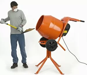 Man shovelling mixture into cement mixer