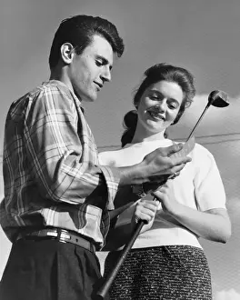 Man showing golf club to woman