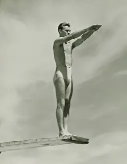 Swimwear Prints: Man on springboard ready to jump, (B&W), low angle view
