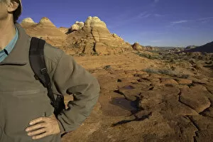 Man standing with hand on hip, sandstone buttes in background