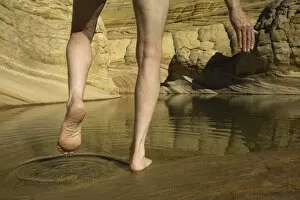 Man stepping into pool of water in sandstone, low section