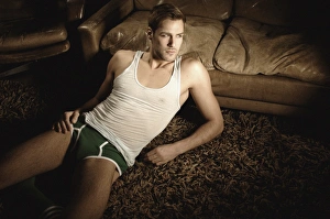 Desire Gallery: Man in underwear lying on the floor in front of a leather sofa