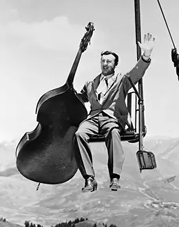 Ski Lift Prints: Man with Upright Bass Riding Ski Lift