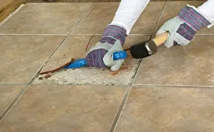 Glove Prints: Man using club hammer and chisel to remove marble tile from floor, close-up