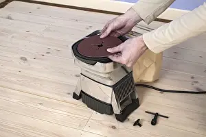 At The Edge Of Prints: Man using hands to position circle of sand paper on edging sander