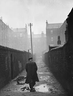 Rear View Gallery: A man walking through a backstreet of the Gorbals area of Glasgow
