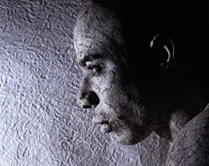 Man wearing face paint, near textured wall, close-up