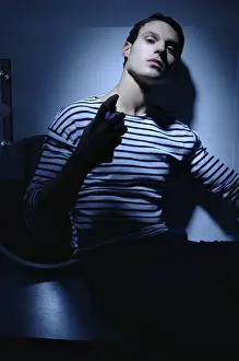 Man wearing a striped T-shirt in a bathroom, spraying on perfume
