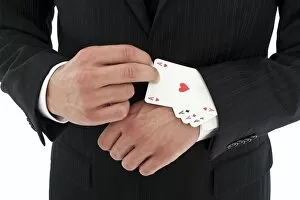 Man wearing a suit pulling several aces out of his sleeve