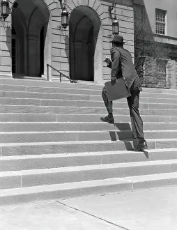 Man wearing suit, running up stairs with briefcase in hand, low section