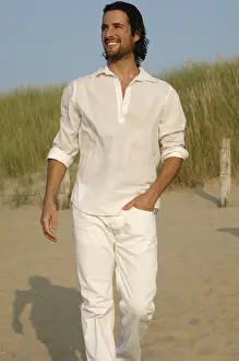 Merry Prints: Man wearing white clothes walking in the dunes on the beach