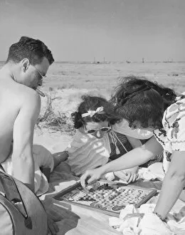 Man and two women playing chinese checkers at beach (B&W)
