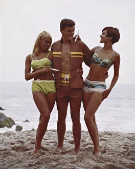 Young Men Gallery: Man with two women standing on beach, smiling