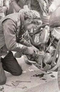 Squatting Prints: Man Works on Oil Gauge on Motorcycle