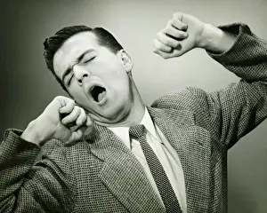 Man yawning and stretching in studio, (B&W)