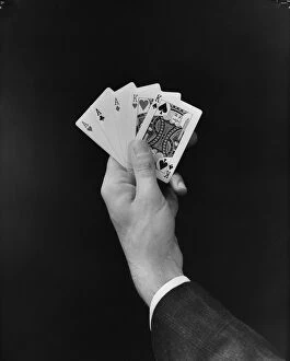 Mans hand holding full house poker card hand. (Photo by H