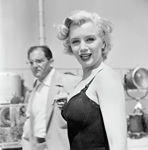 Prints of (Original Caption) 7/1/1952: Portrait of Marilyn Monroe in bathing suit. Unidentified man in background Marilyn Monroe: A Fashion Legacy: Marilyn Monroe In Bathing Suit
