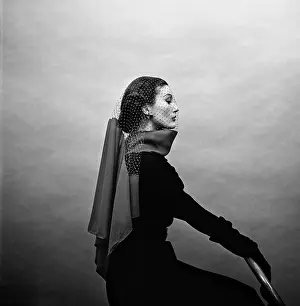 Prints of NEW YORK CITY, NEW YORK - 1951 : Fashion model Mary Jane Russell sits on a chair side profile with her hands straight holding another chair with veil over her face and scarf around her neck Hollywood's Sultry Siren – A Photographic Tribute: Mary Jane Russell