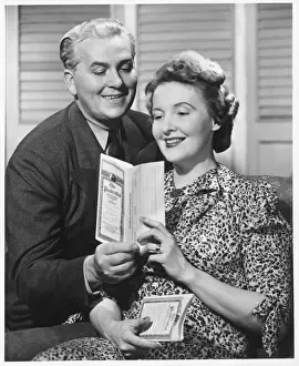 Mature couple looking at brochure, (B&W)