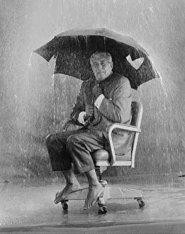 Images Dated 30th July 2011: Mature man holding torn umbrella in rain