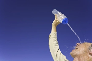 New Mexico Collection: Mature man pouring water over face under clear sky, low angle view