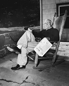 Mature man in rocking chair with pipe and newspaper (B&W)