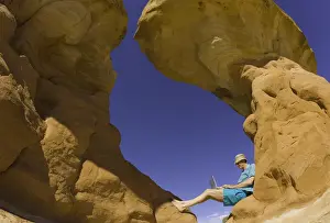 Typing Prints: Mature man sitting on rock formation, working on laptop computer