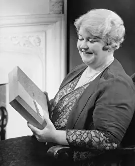 50 59 Years Prints: Mature woman holding gift in living room, (B&W)