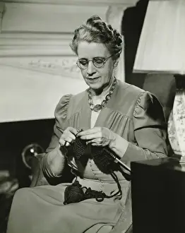 50 59 Years Prints: Mature woman knitting in living room, (B&W)