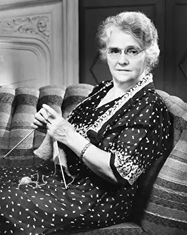 One Senior Woman Only Prints: Mature woman knitting in living room (B&W), portrait