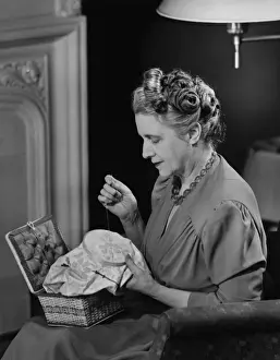 Mature woman sitting in living room, doing needlepoint, (B&W)