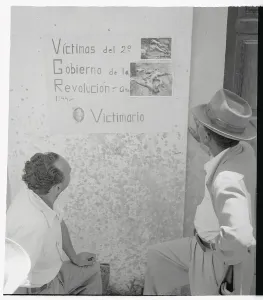 Guatemala Prints: Two Men Looking at Poster on Wall