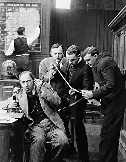 Men Reading Stock Ticker Tape