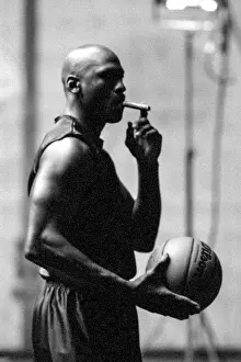 Prints of Michael Jordan holds a Wilson basketball while smoking a cigar and wearing a sleeveless Nike shirt on the set of a television commercial surrounded by grip Timeless Moments: A Visual Journey Through History’s Defining Images: Michael Jordan 23