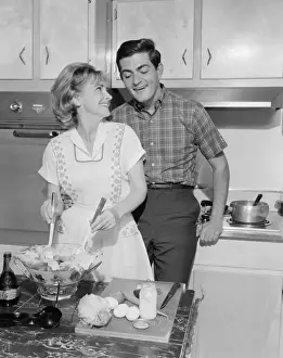 Mid adult couple in kitchen, woman preparing salad