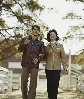 Mid adult couple walking with arm in arm, smiling