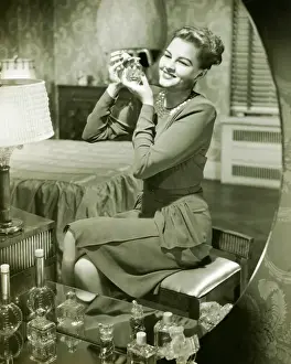 Mirror reflection of woman applying perfume at vanity table, (B&W)
