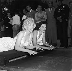 Prints of American actresses Marilyn Monroe (1926 - 1962) (left) and Jane Russell lay on their stomachs, about to press their hands into wet cement at Grauman's Chinese Theatre in Hollywood, California Hollywood's Sultry Siren – A Photographic Tribute: Monroe And Russell
