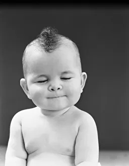 Eight month old baby girl with thoughtful expression, eyes closed and lips pursed Eight month old baby girl with thoughtful expression, eyes closed and lips pursed
