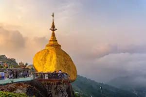 Morning Landscape sunrise view with fog of Kyaiktiyo pagoda (Golden Rock) at twilight with praying people and tourists. Kyaiktiyo, Myanmar